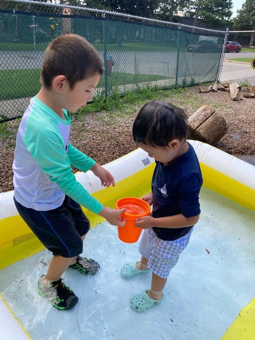 Two young boys are playing in an inflatable pool.