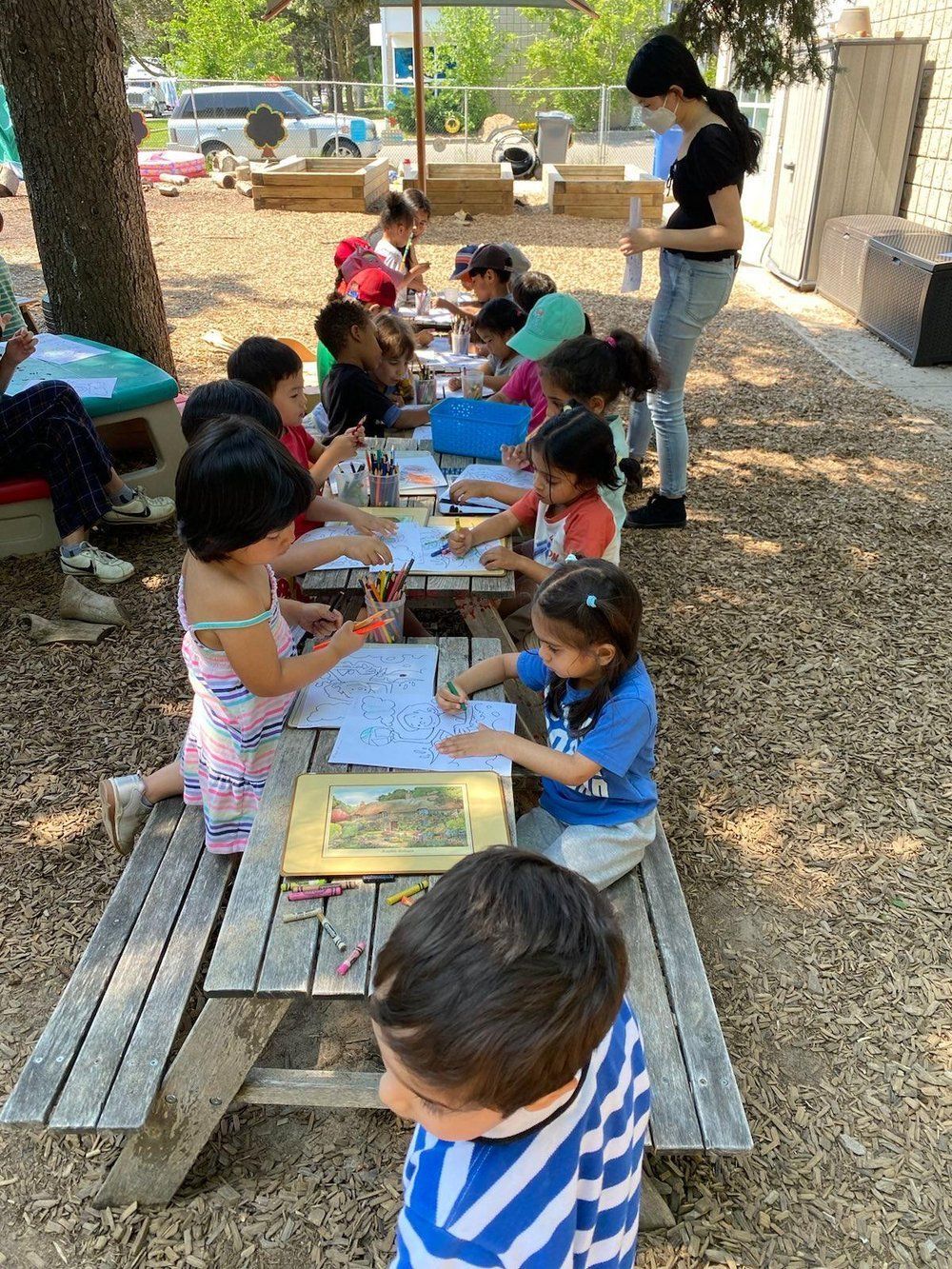 A group of children are sitting at a picnic table outside.
