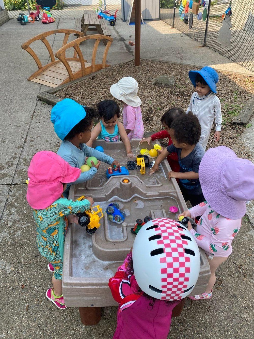 A group of children are playing with toys on a sand table.