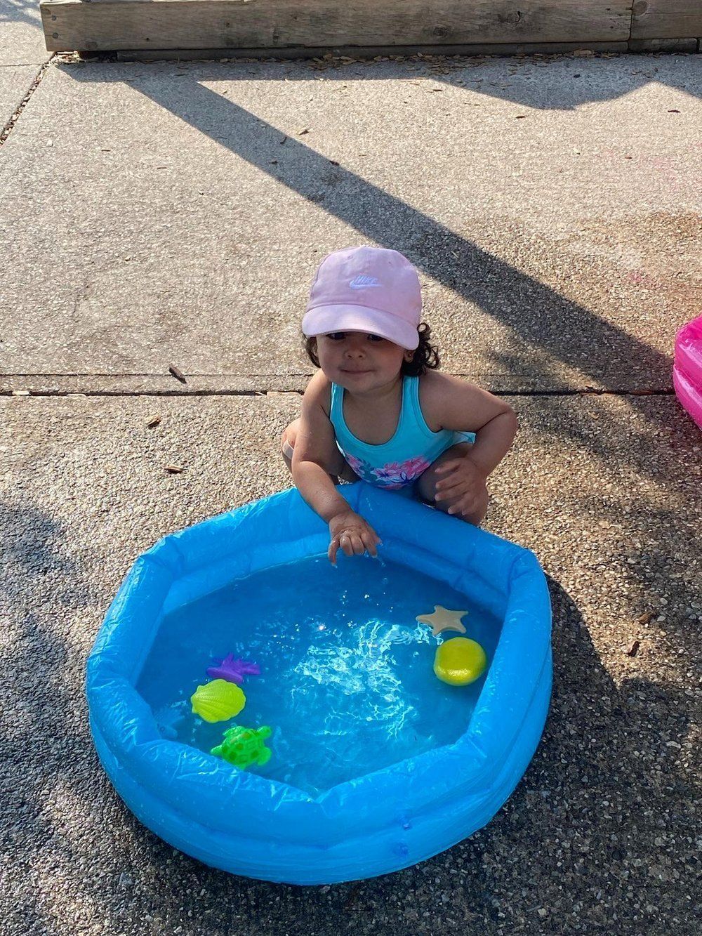 A little girl is playing in an inflatable pool.