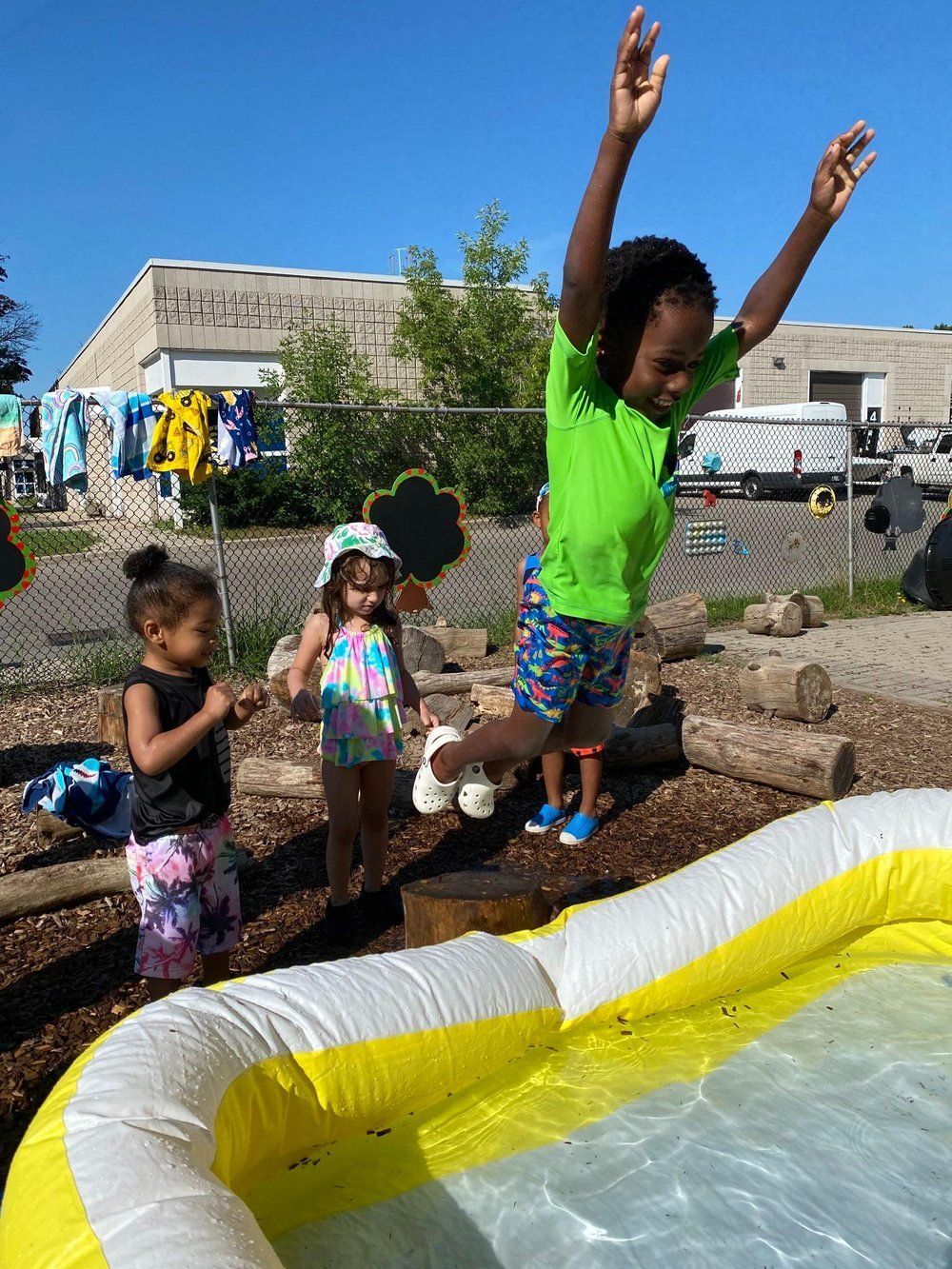 A young girl is jumping into an inflatable pool.