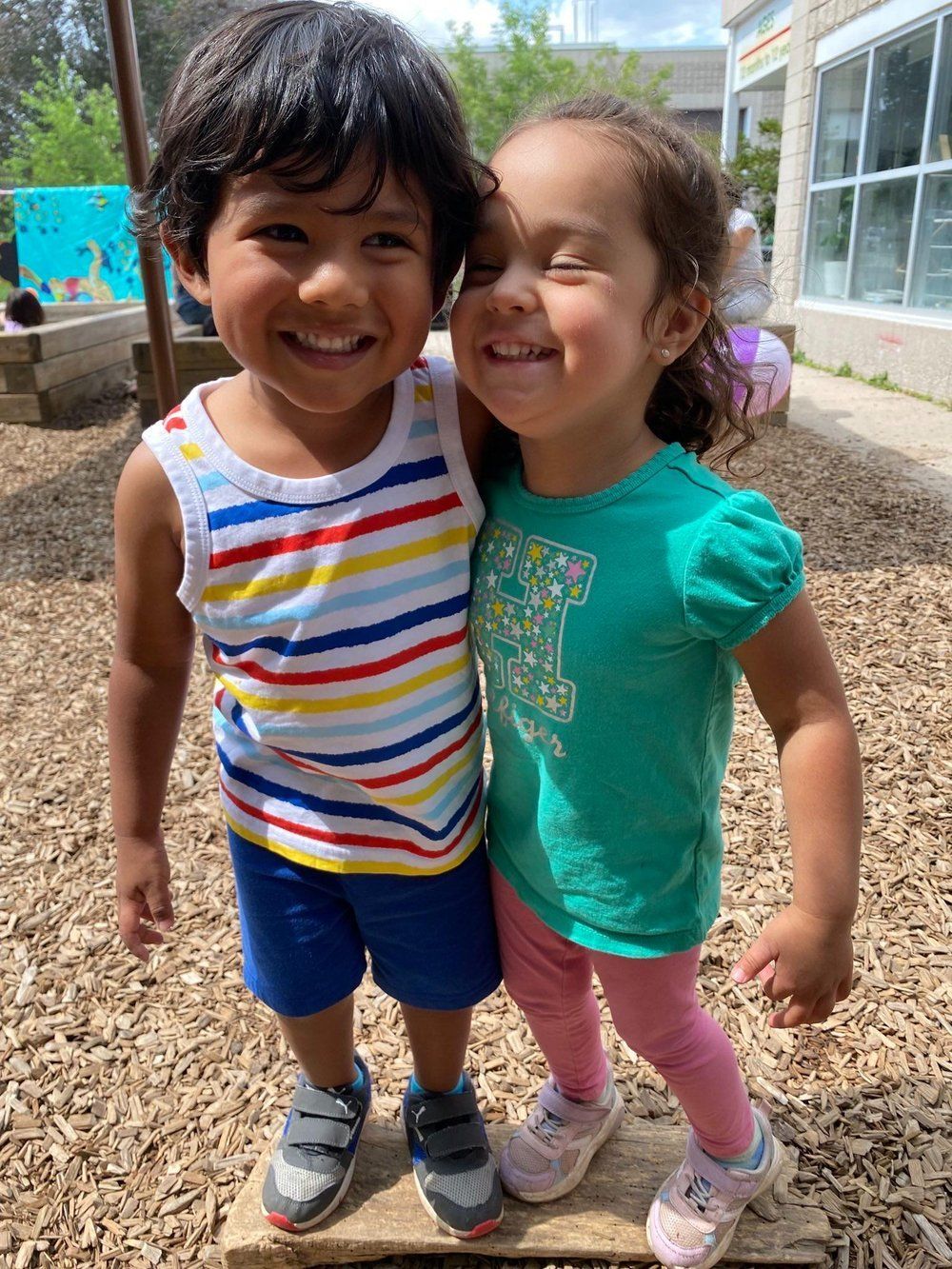 A boy and a girl are standing next to each other and smiling.