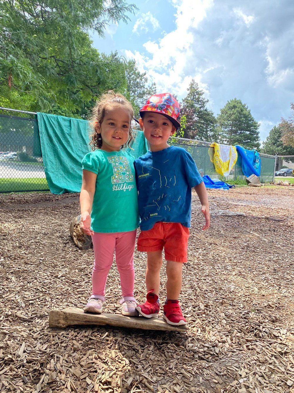 A boy and a girl are standing next to each other on a log.