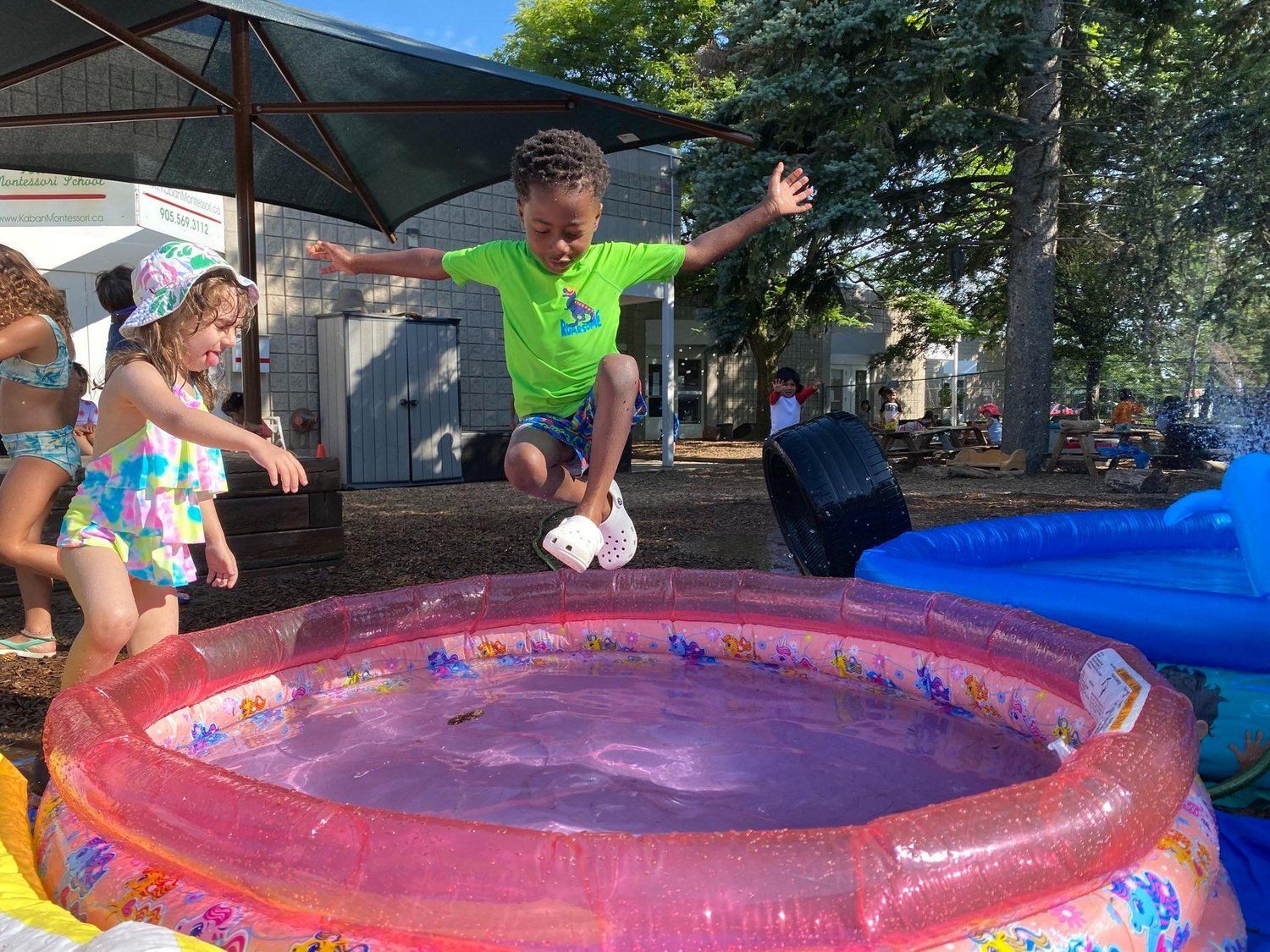 A young boy is jumping into an inflatable pool.