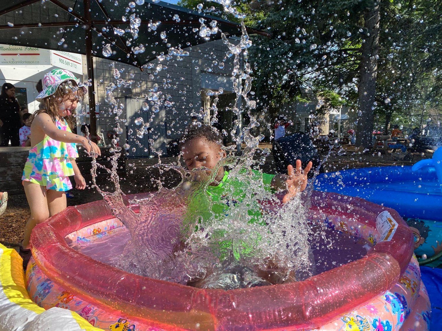 A little girl is splashing water in an inflatable pool.