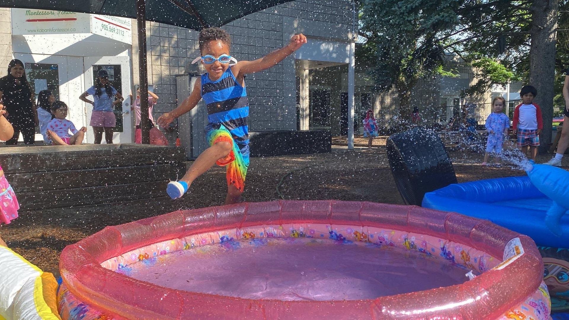 A little girl is jumping into an inflatable pool.