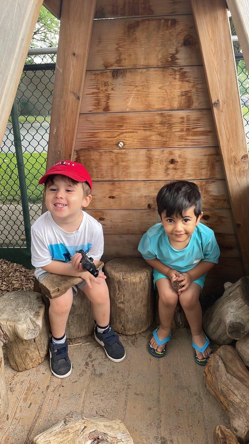 Two young boys are sitting next to each other in a wooden structure.