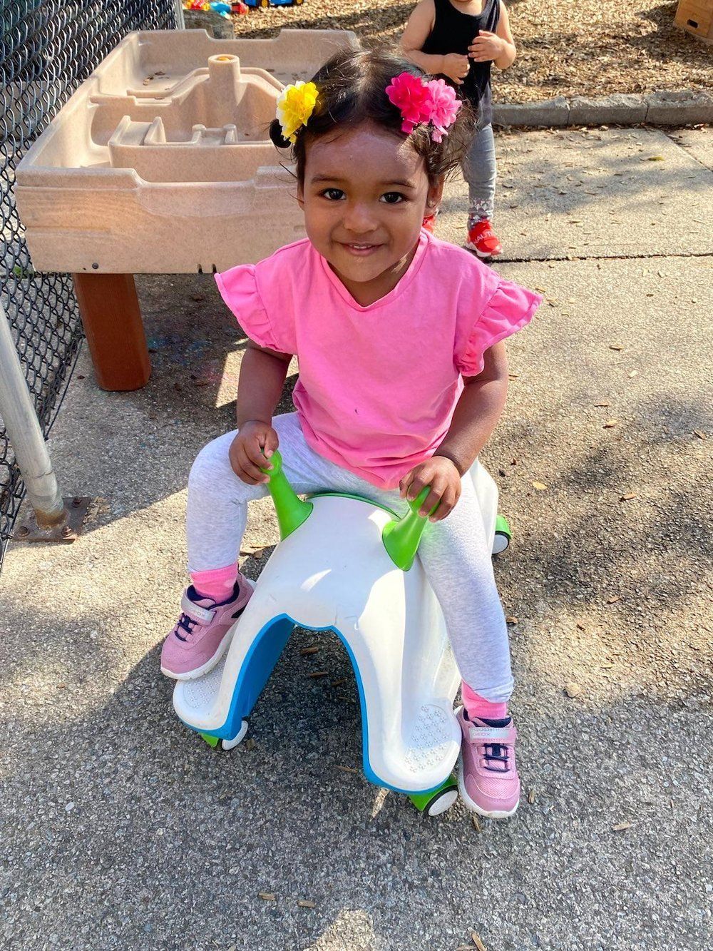 A little girl is sitting on a rocking horse in a playground.