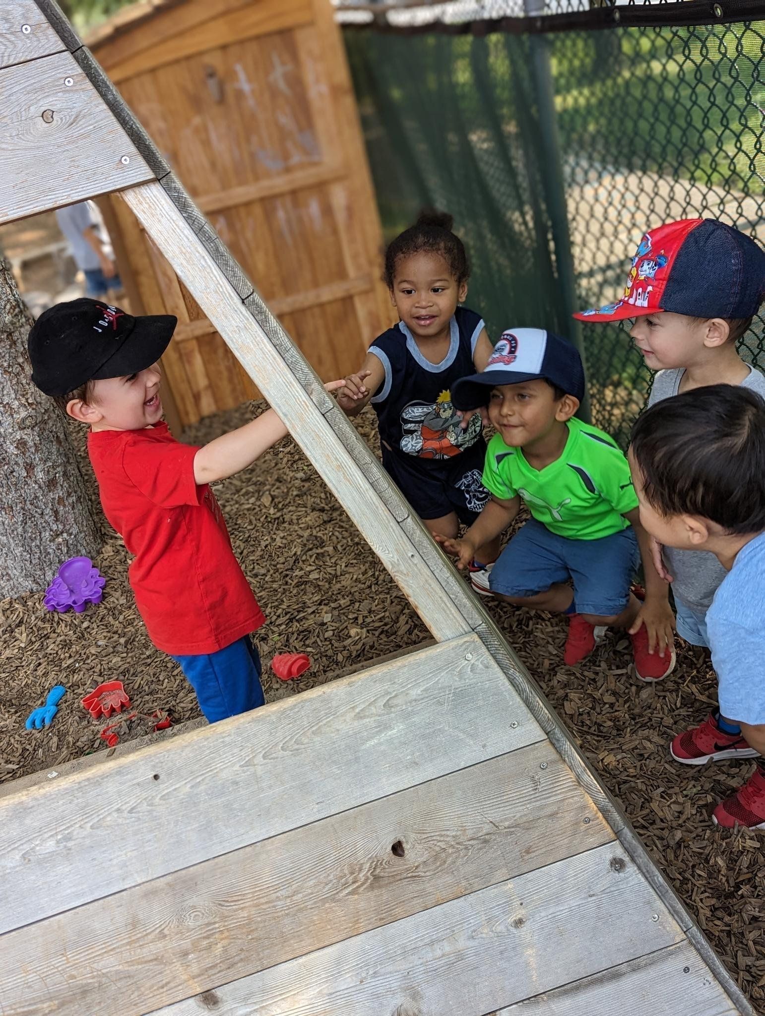 A group of young boys are playing in a sandbox.