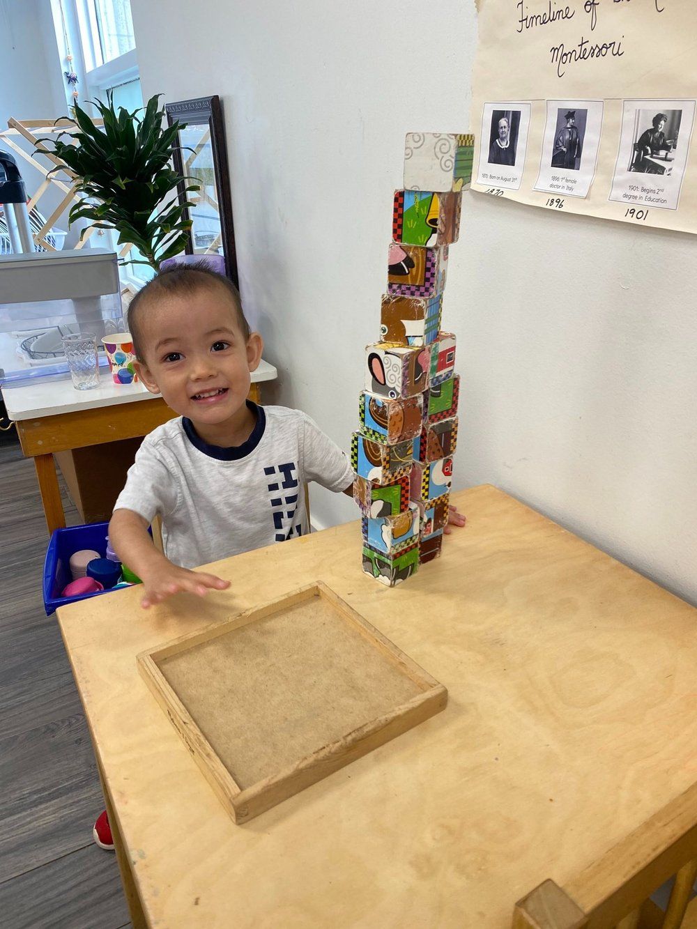 A young boy is sitting at a table holding a stack of blocks.
