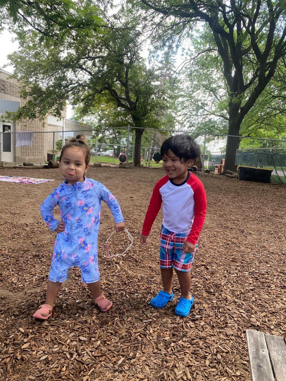 A boy and a girl are standing next to each other in a playground.