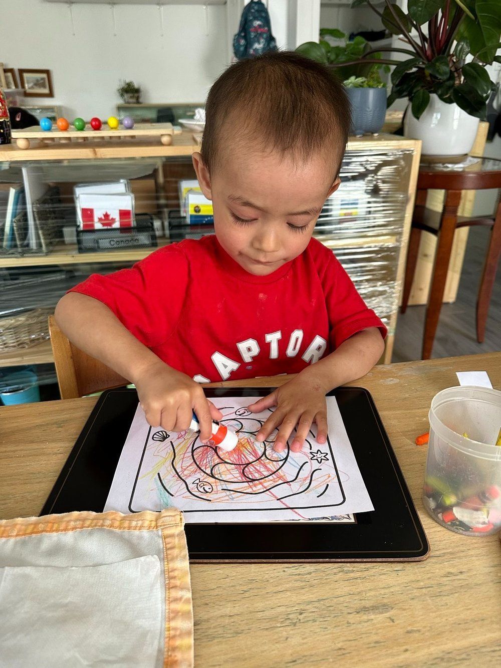 A young boy in a red shirt is sitting at a table.