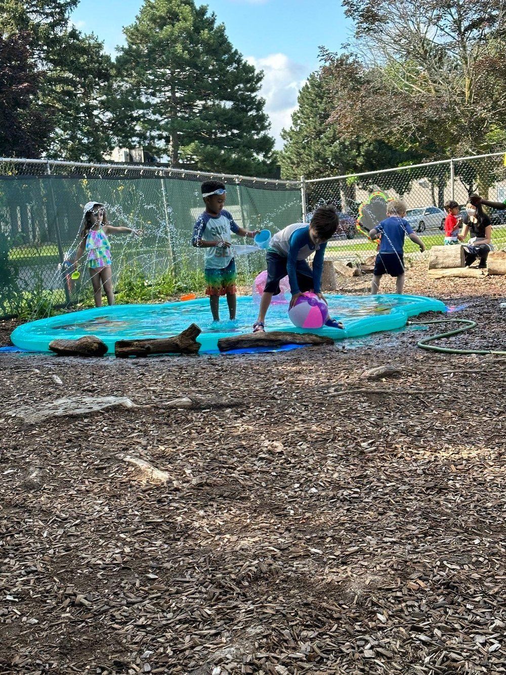 A group of children are playing in a water slide in a park.