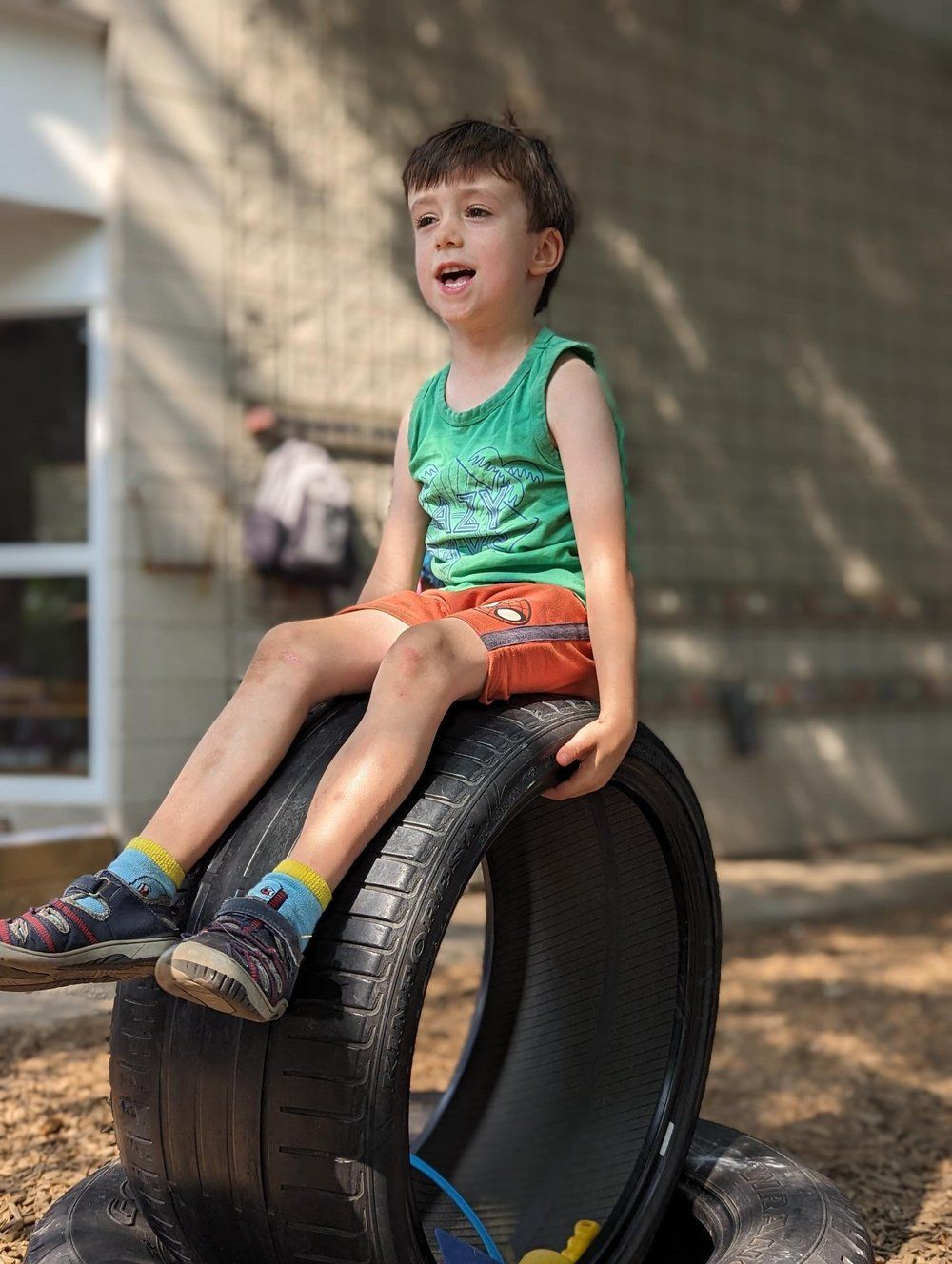 A young boy is sitting on top of a tire.