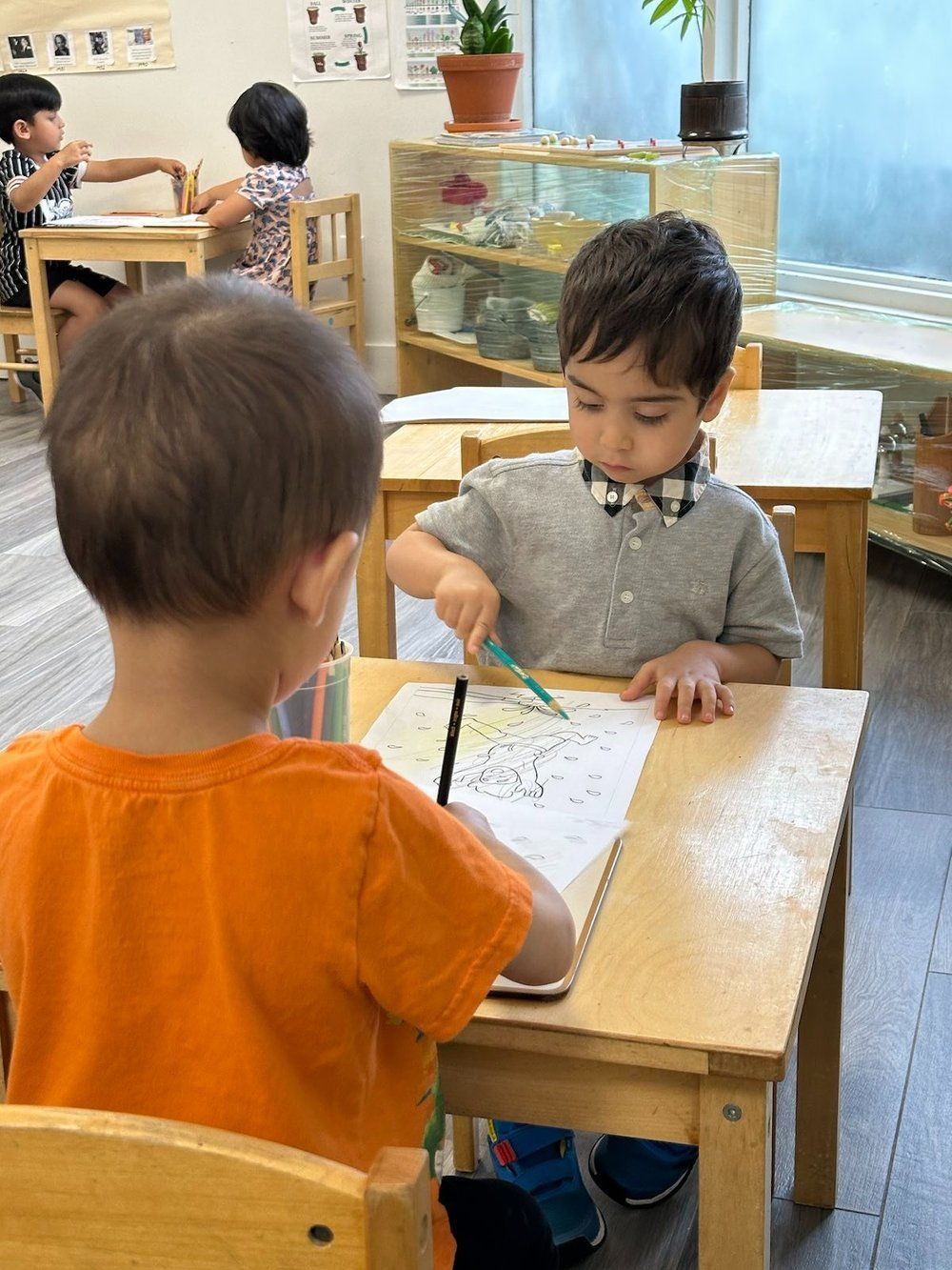 Two young boys are sitting at wooden desks in a classroom.