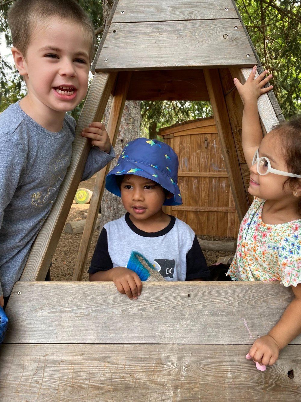 A boy and a girl are playing in a wooden playhouse.