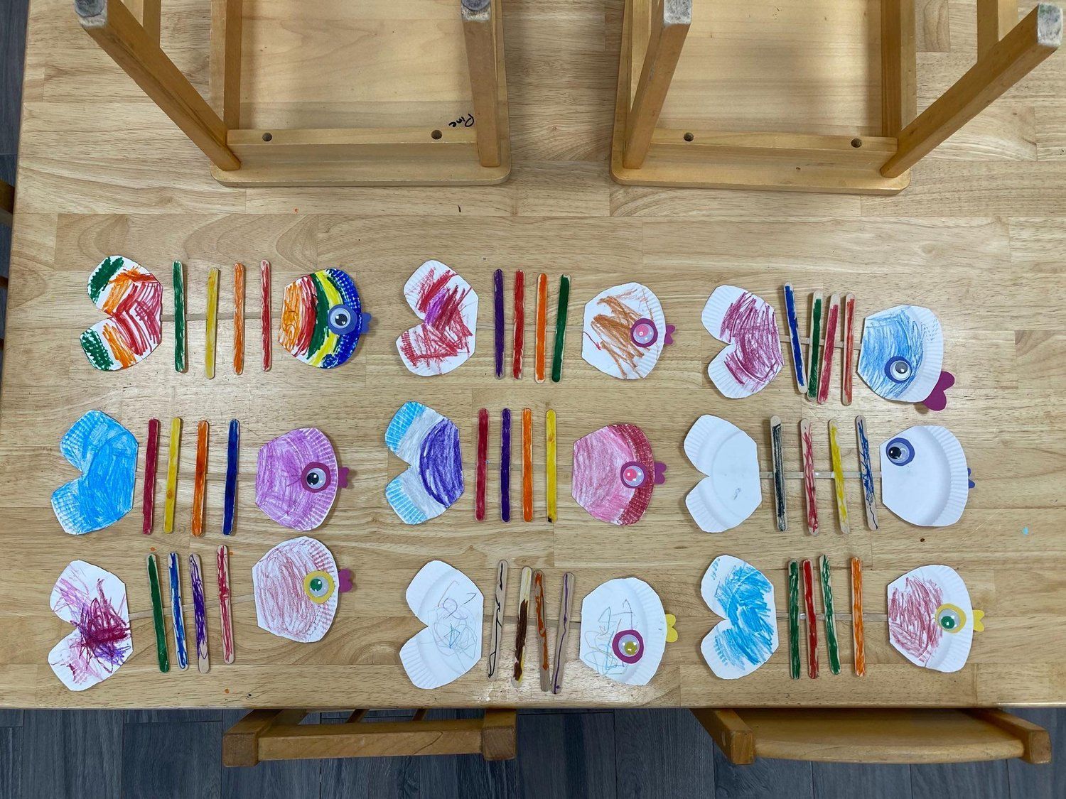 A wooden table with a bunch of crayons on it.