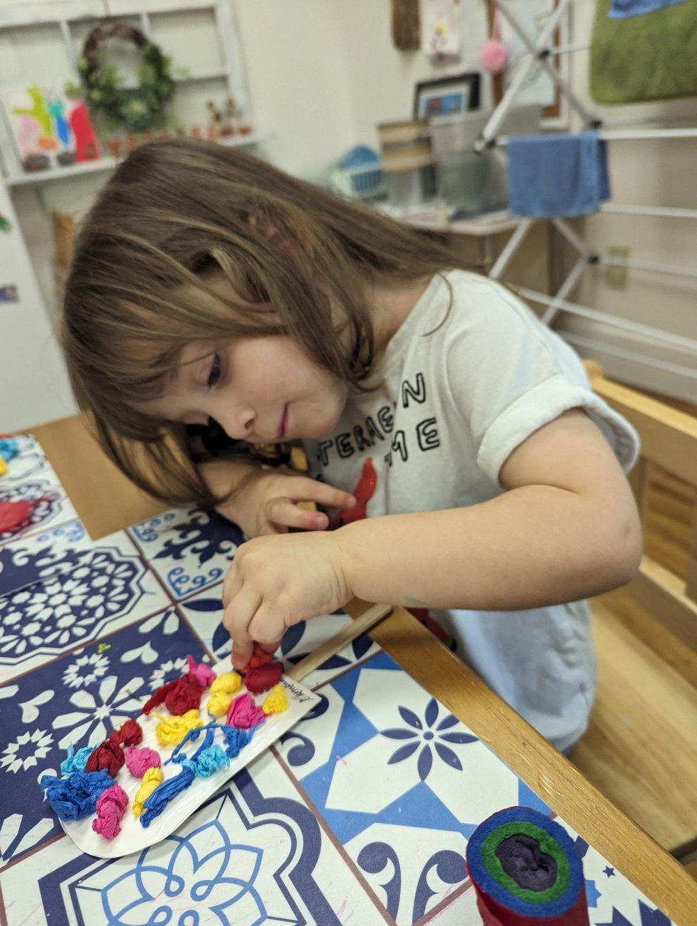 A little girl is sitting at a table painting