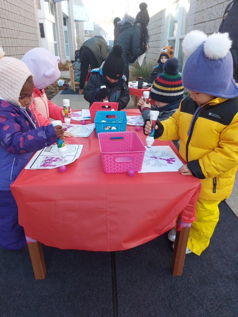 A group of children are sitting at a table playing with glue.