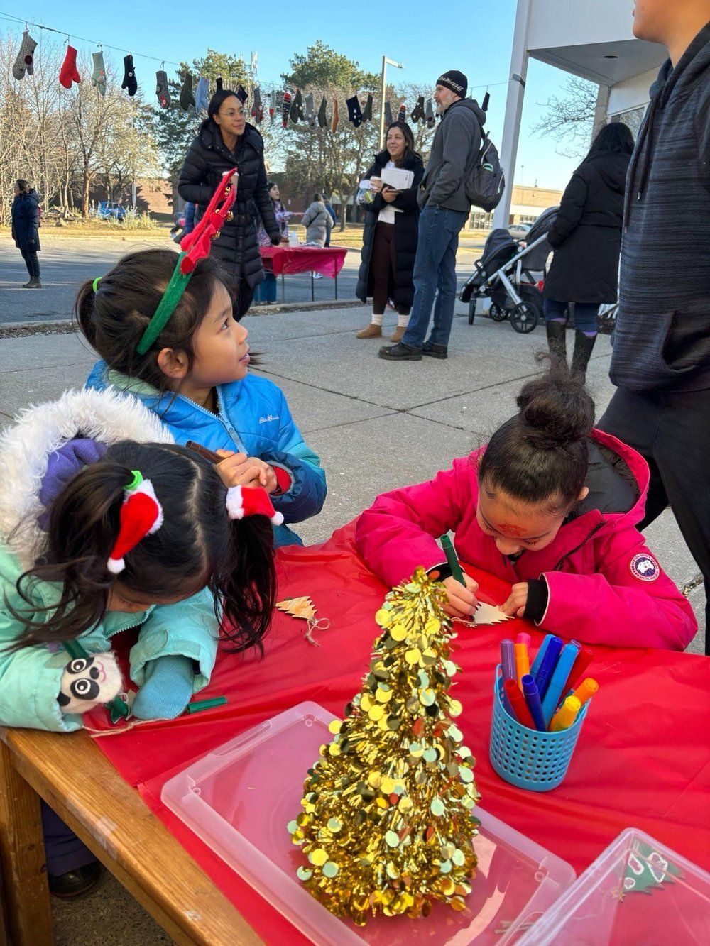 A group of children are sitting at a table decorating a christmas tree.