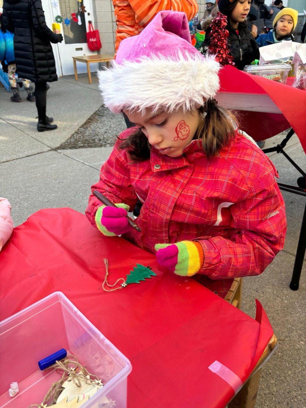 A little girl wearing a santa hat is sitting at a table