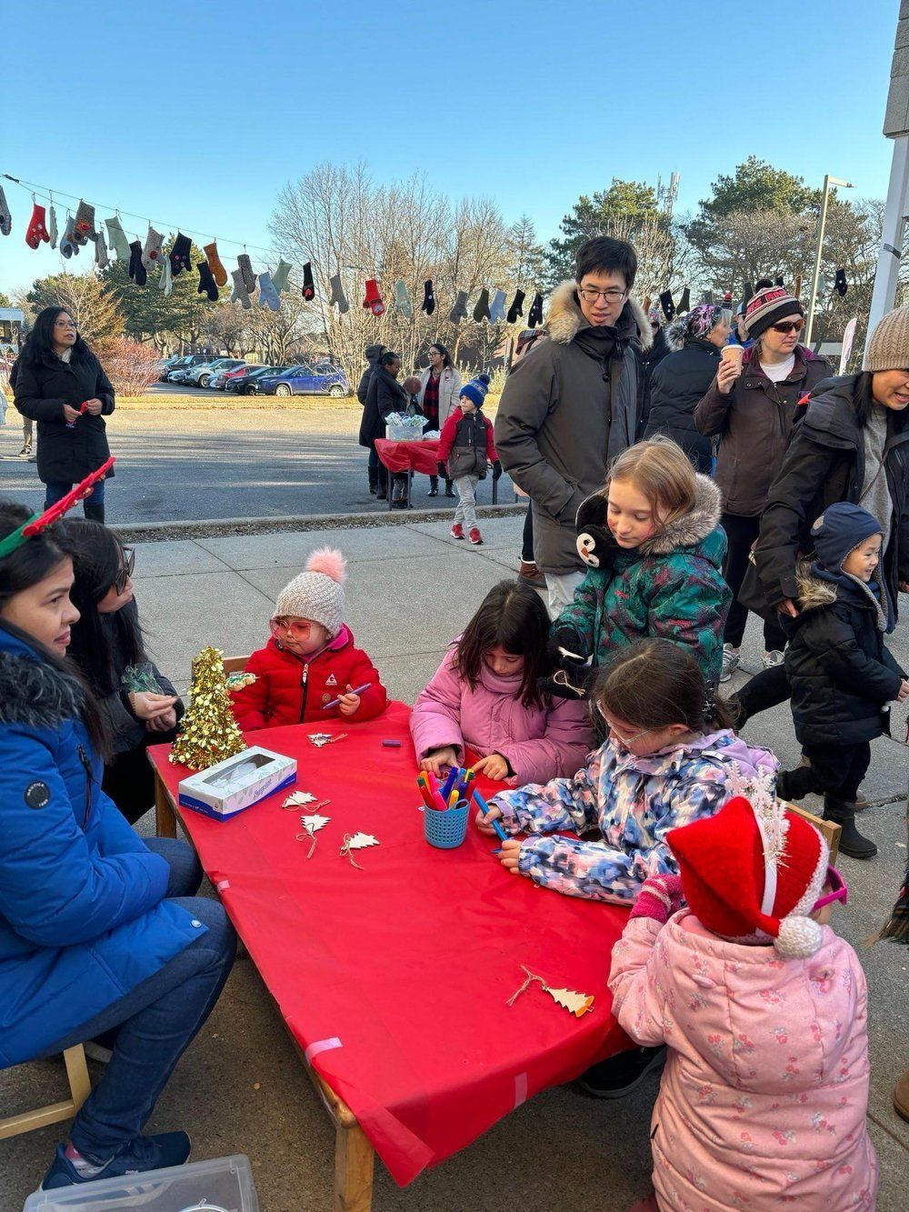 A group of children are sitting at a table making christmas decorations.