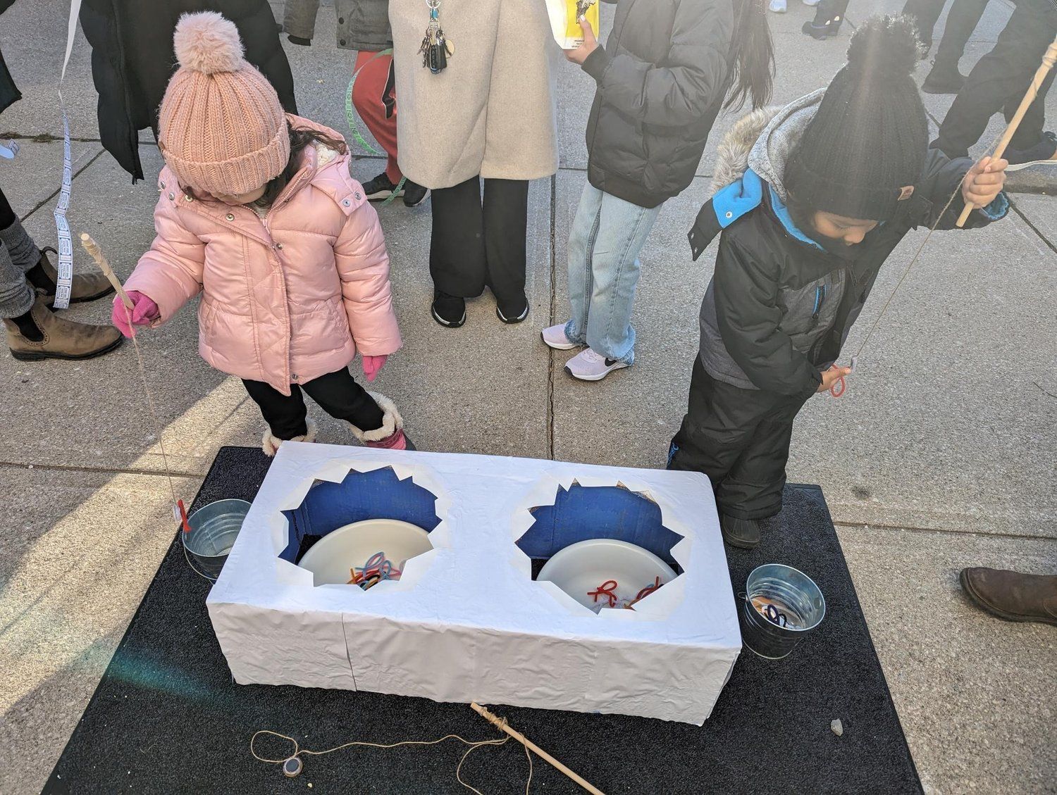 A girl in a pink jacket is standing next to a boy in a black jacket.