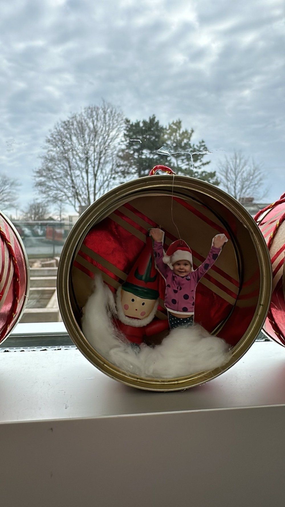 A christmas ornament is sitting on a window sill.