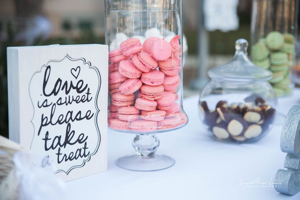 Candy bar with pink macarons in a glass jar, a sign that says