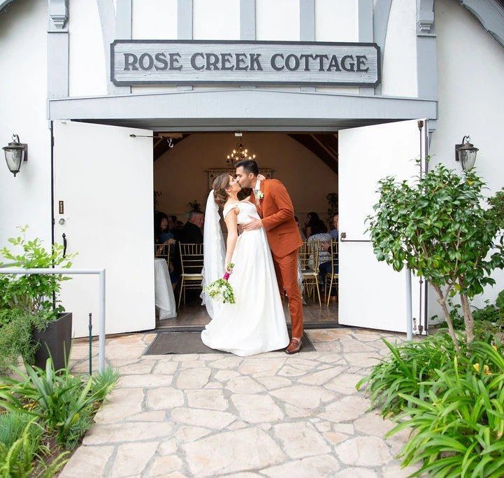 Couple kissing at Rose Creek Cottage wedding entrance.