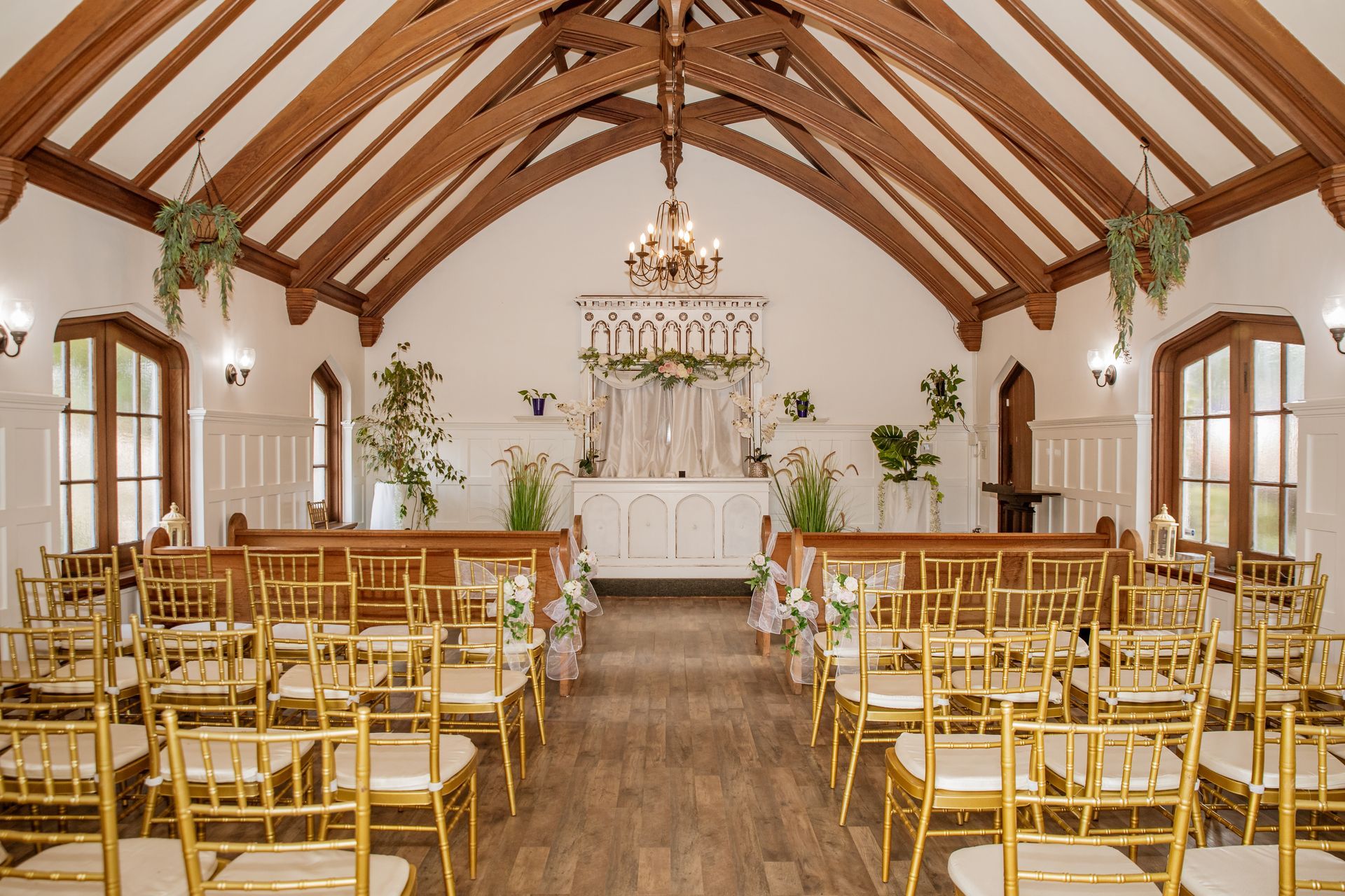A wedding chapel interior with gold chairs, wooden beams, and floral decorations.