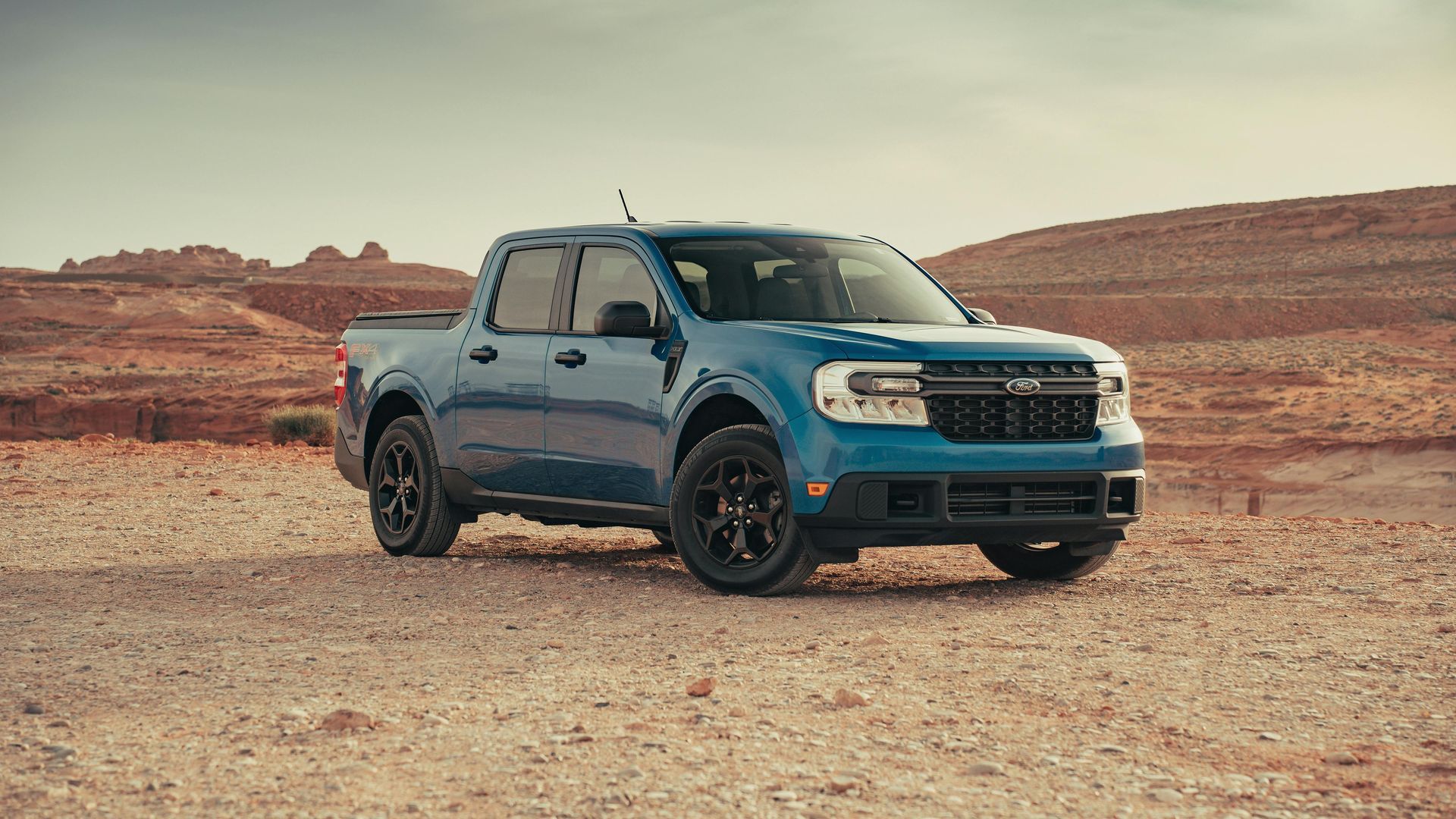A blue truck is parked in the middle of a desert.