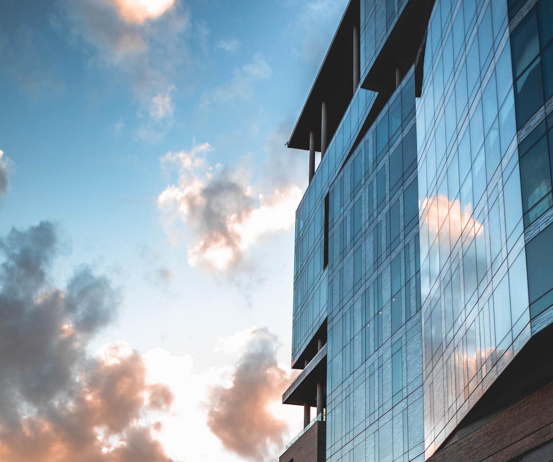 A tall building with a lot of windows against a cloudy sky.