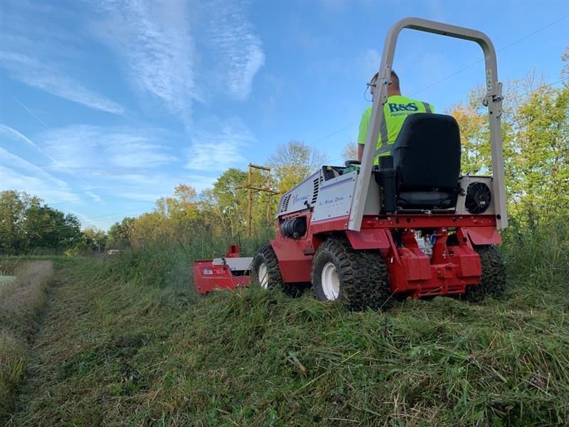 an R&S Property Services lawn care expert cutting grass with a large riding lawnmower