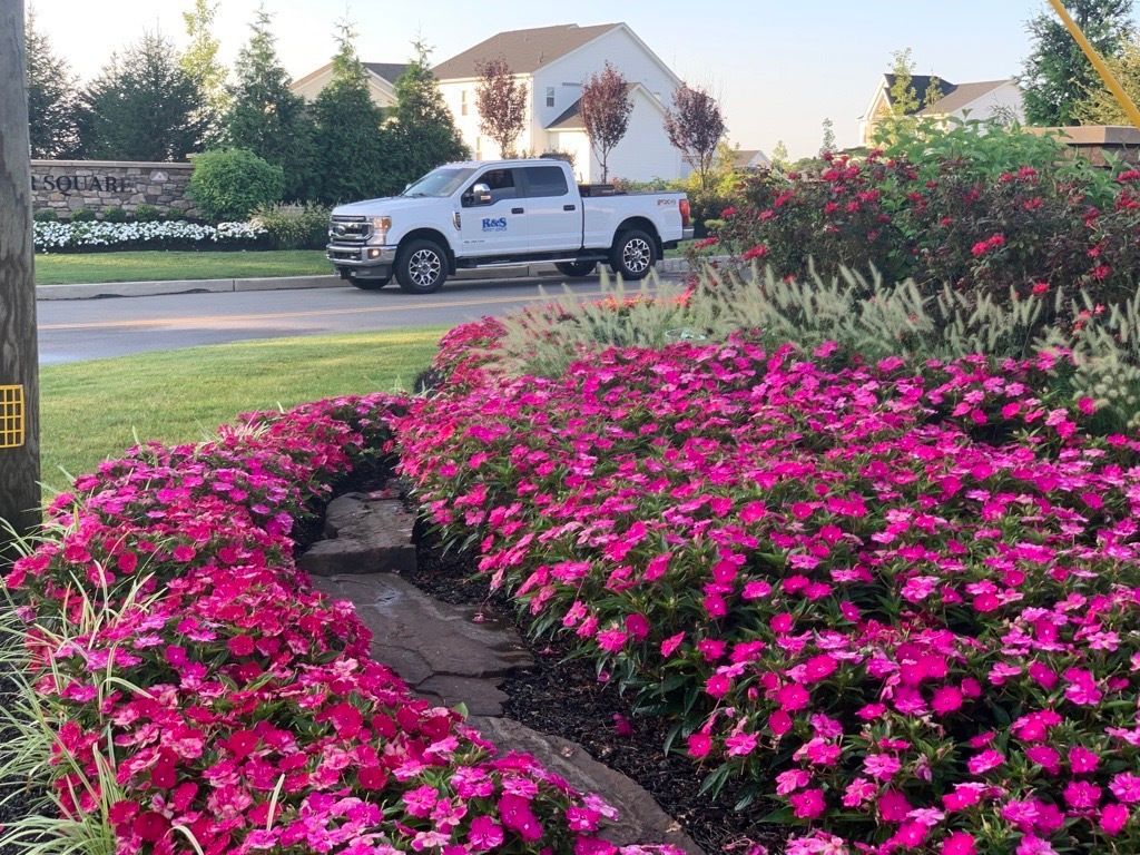 a seasonal flower display in front of an R&S Property Services work truck