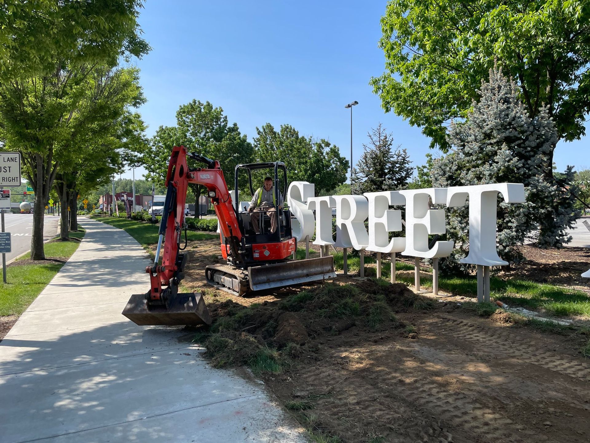 An R&S Property Services landscape design installer using an excavator to remove old grass at a Malvern, PA commercial property