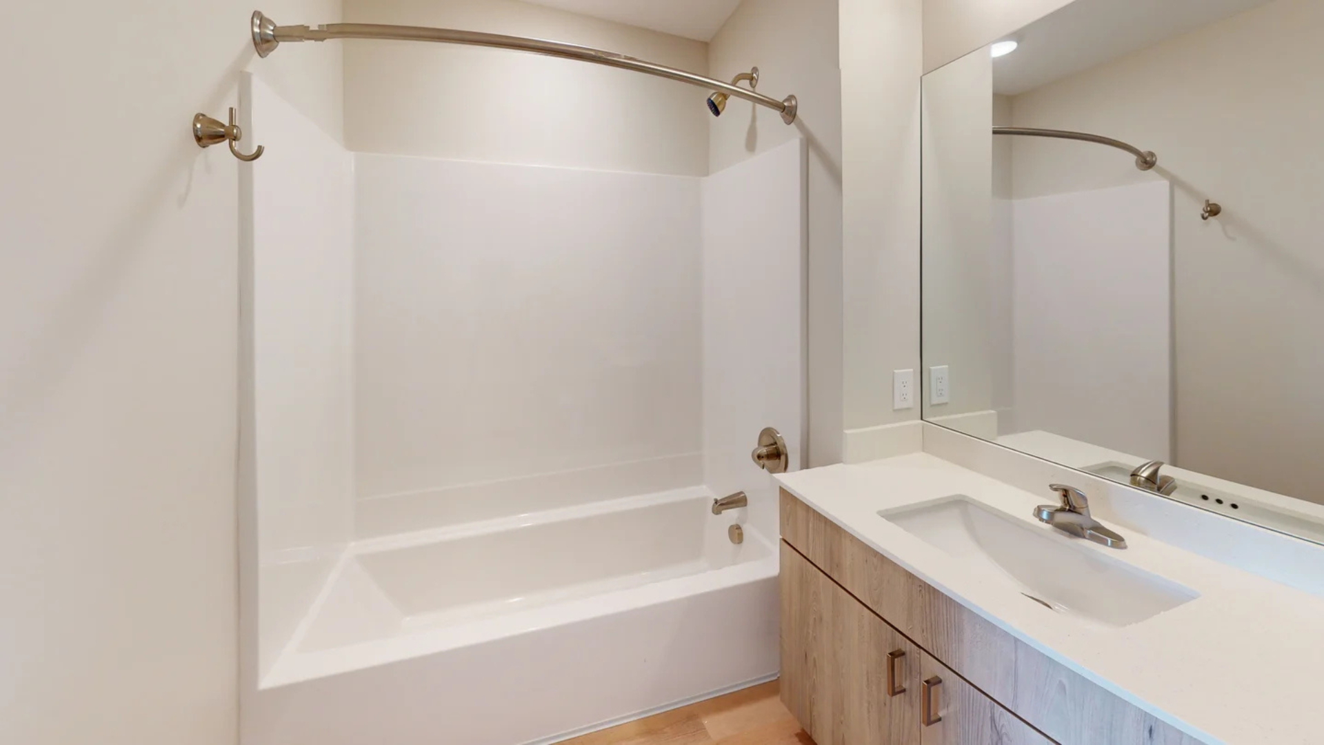 Bathroom with white tub/shower, vanity, and large mirror.
