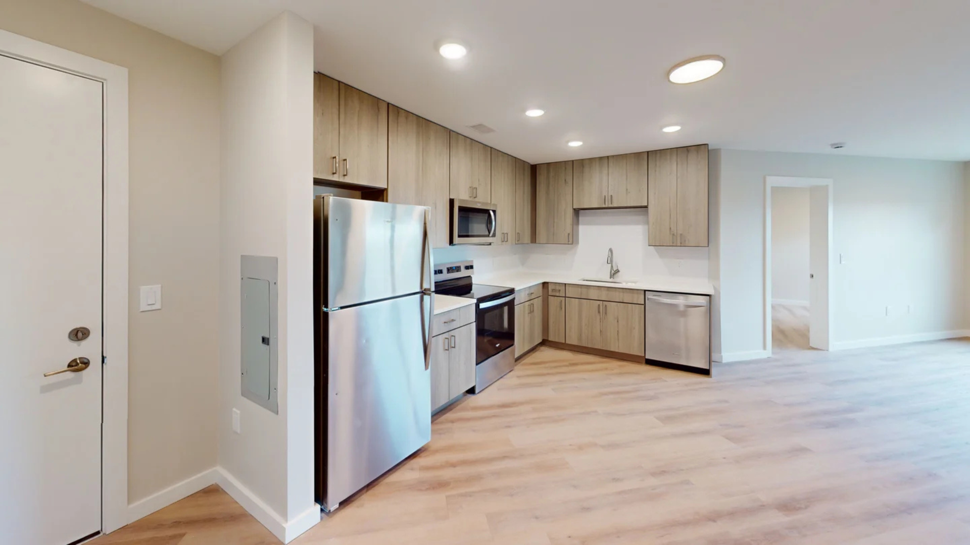 Kitchen with stainless steel appliances, light wood cabinets, and light wood flooring.