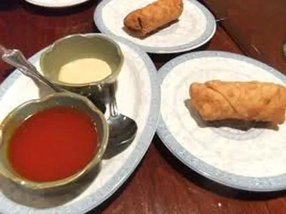 Three plates of food with sauces and a spoon on a table.