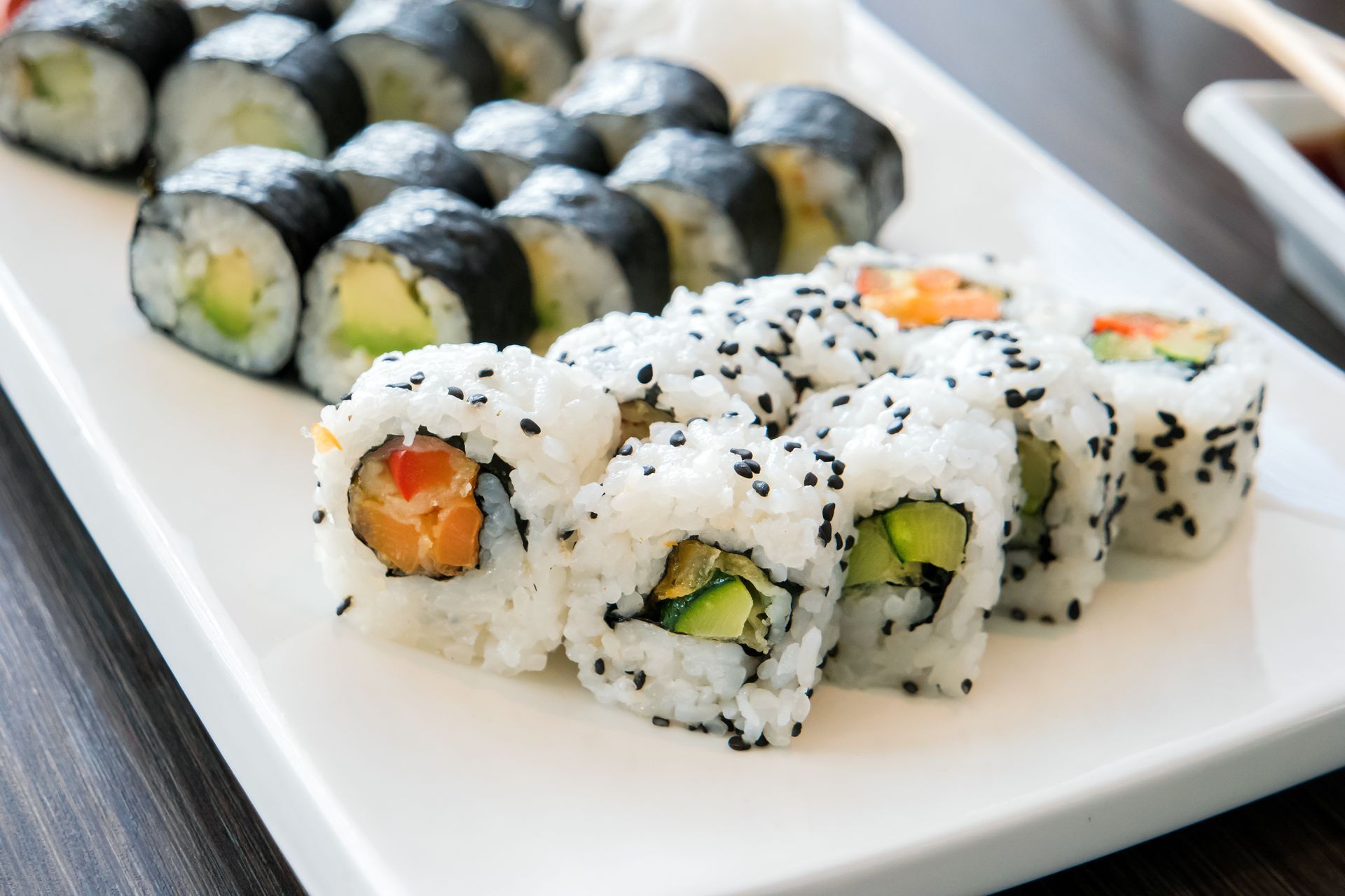 A white plate topped with a variety of sushi rolls