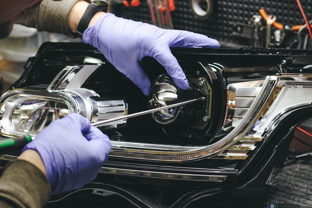 A Person Wearing Purple Gloves is Working on a Car Headlight — CS Mechanical in Gormans Hill, NSW