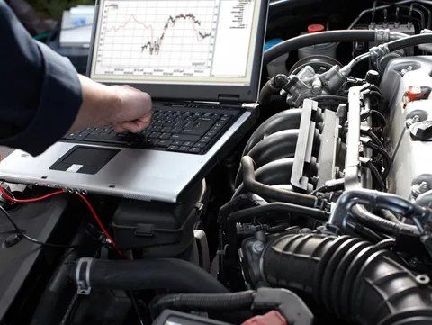 A Man is Working on a Car Engine With a Laptop — CS Mechanical in Gormans Hill, NSW