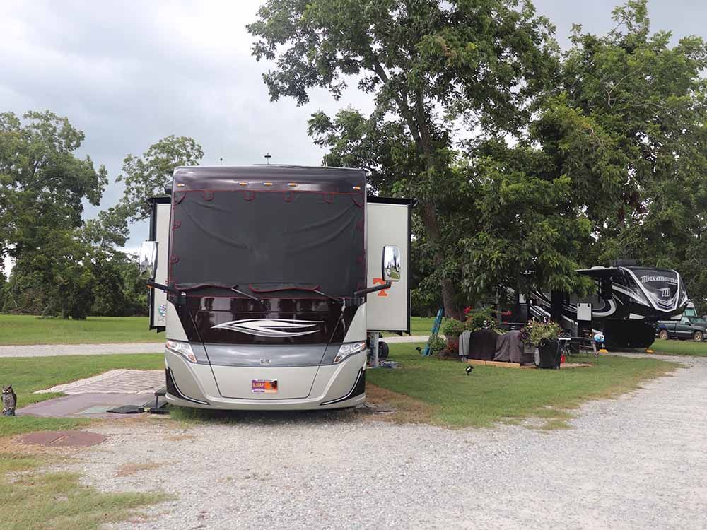 A large rv is parked in a grassy area with trees in the background.