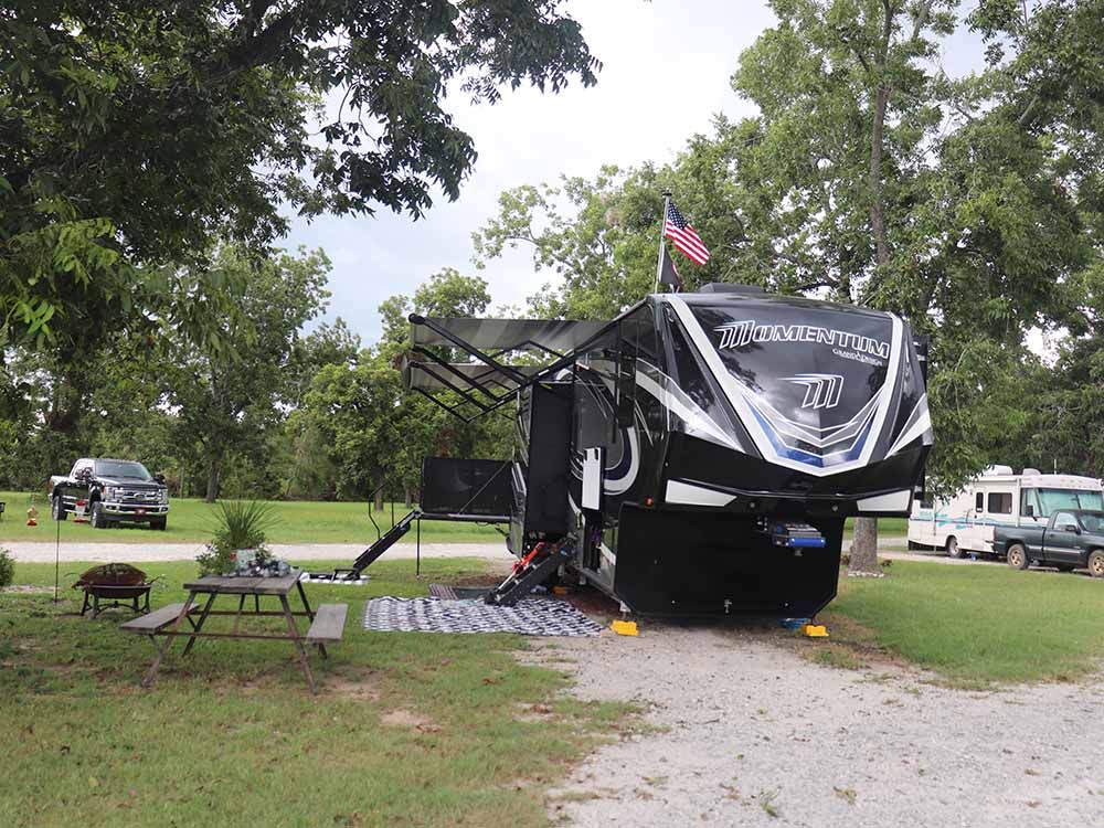 A large rv is parked in a grassy area next to a picnic table.