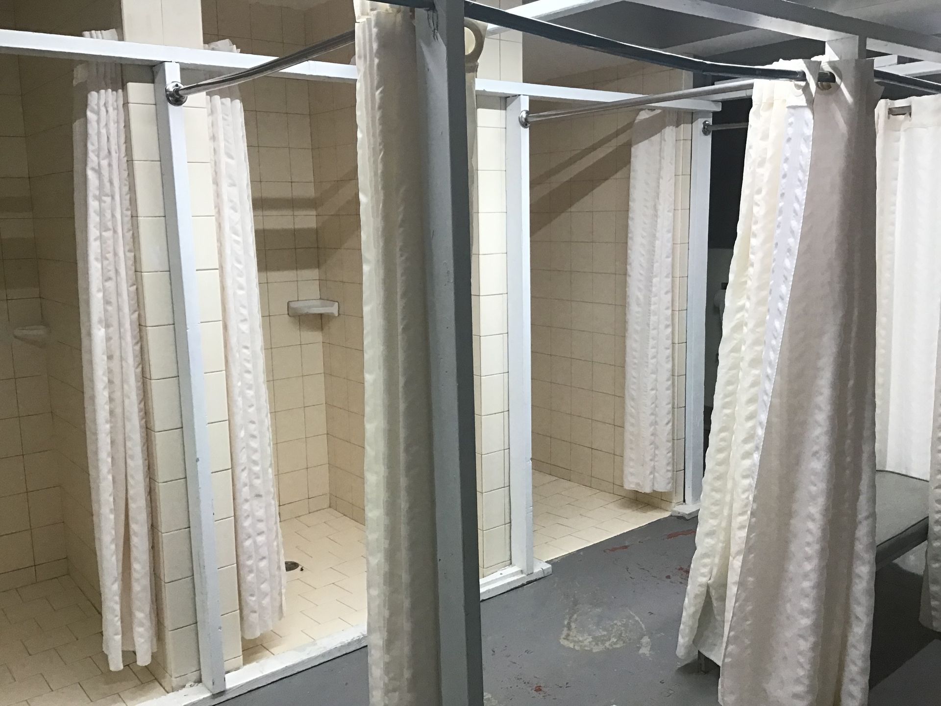 A bathroom with shower curtains hanging from the ceiling