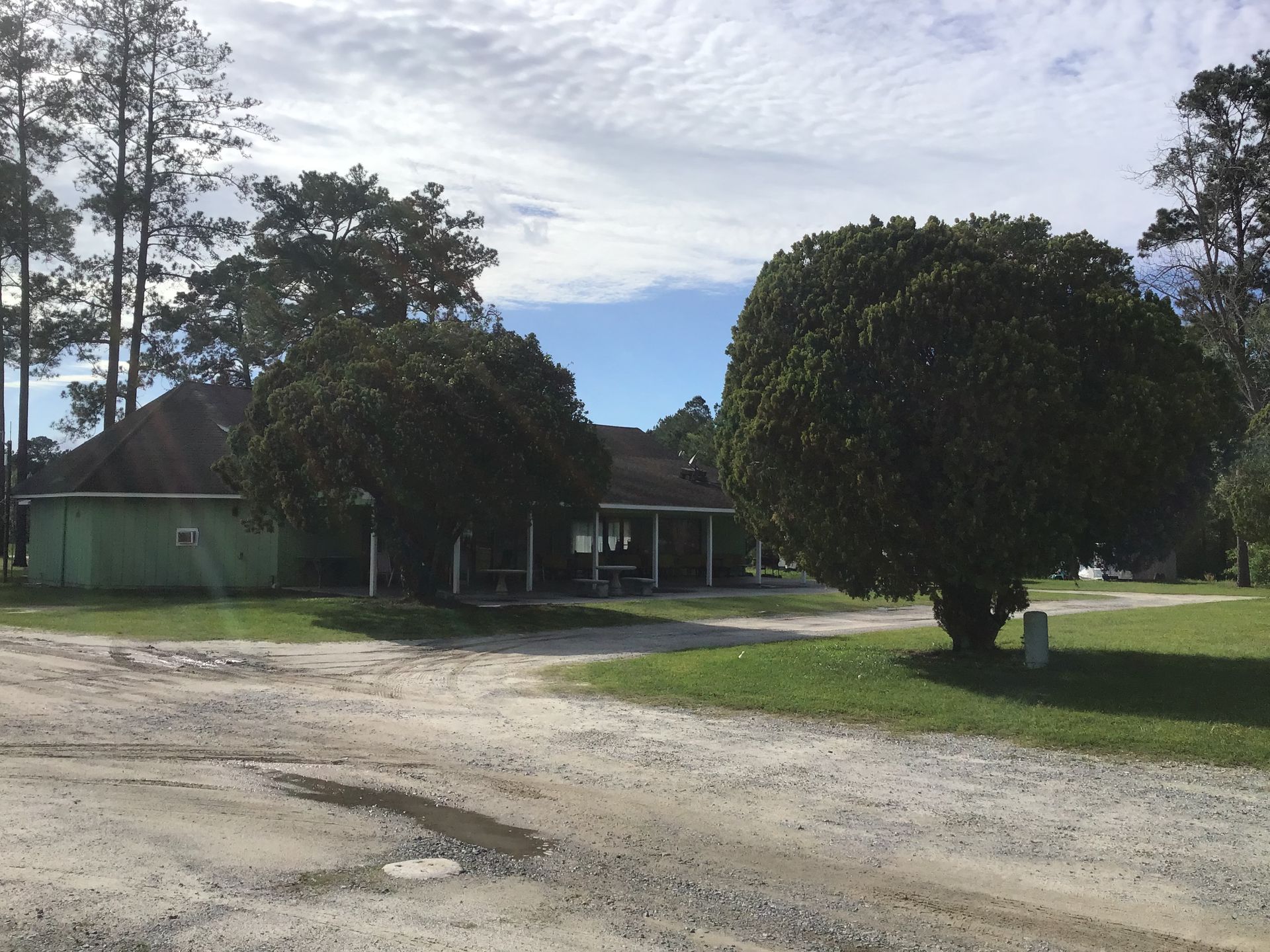 A dirt road leading to a house with trees in front of it