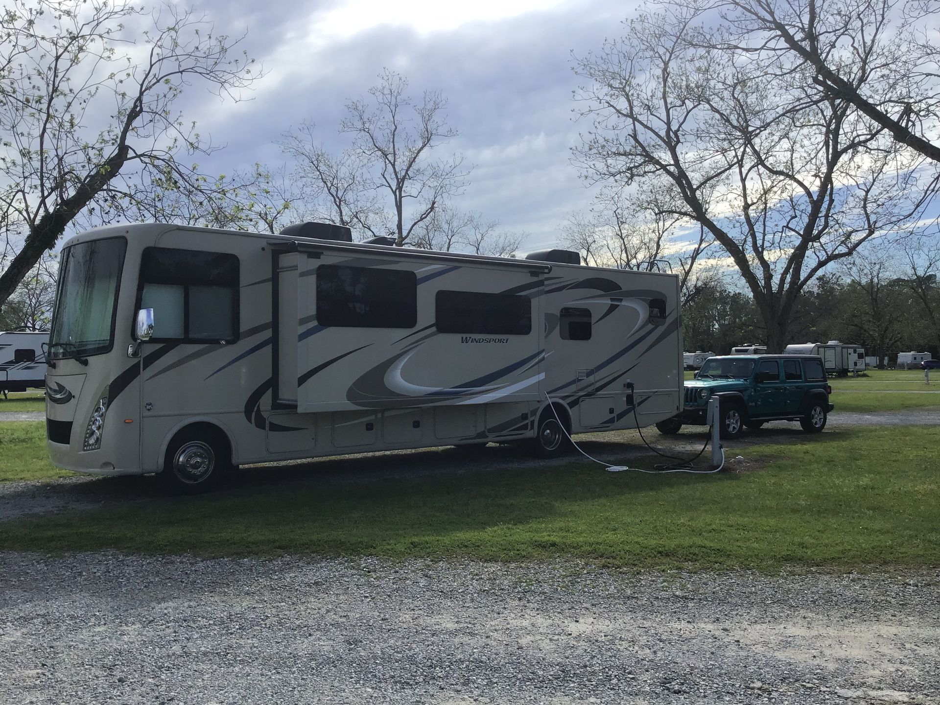 A large white rv is parked in a gravel lot.
