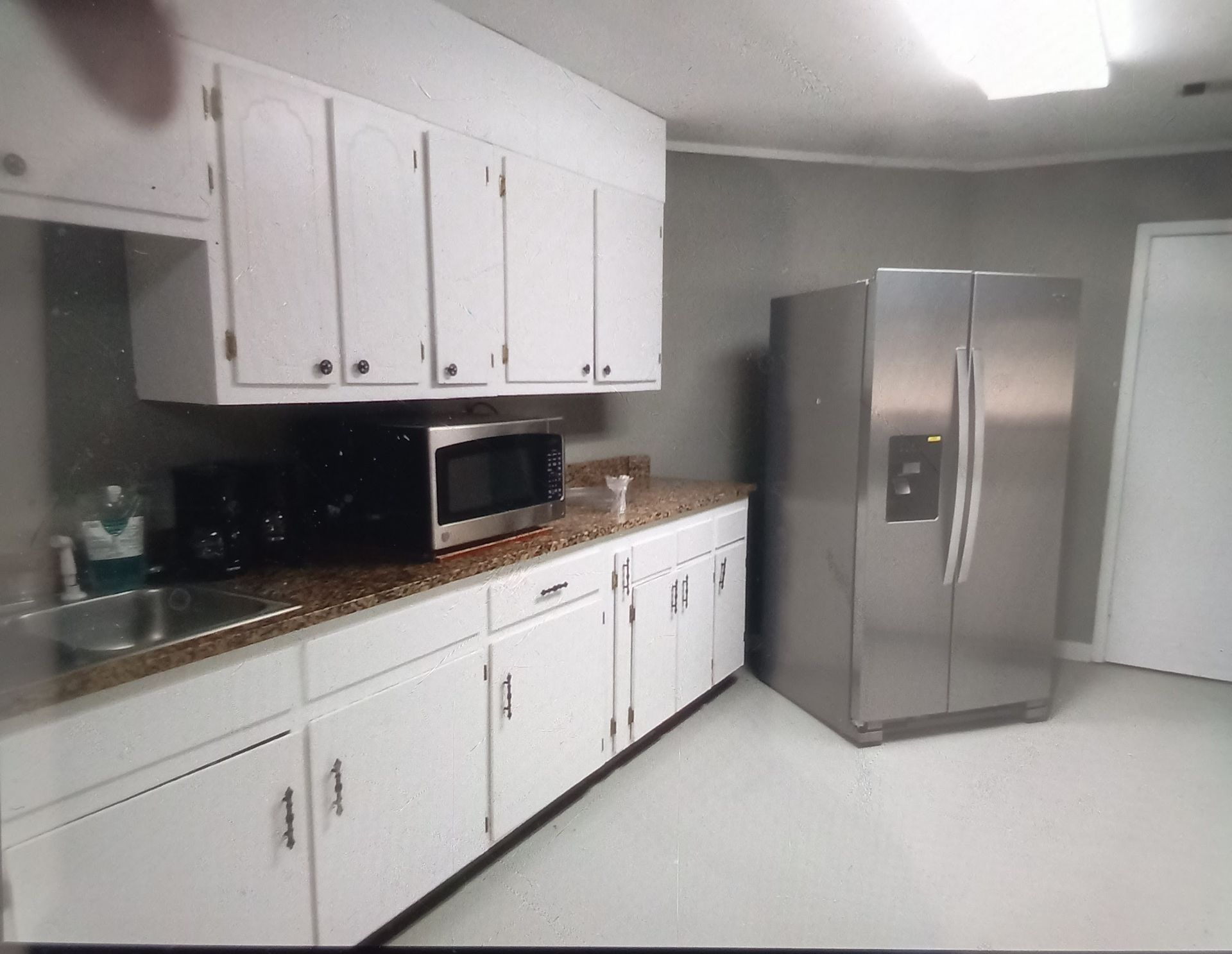A kitchen with white cabinets and a stainless steel refrigerator