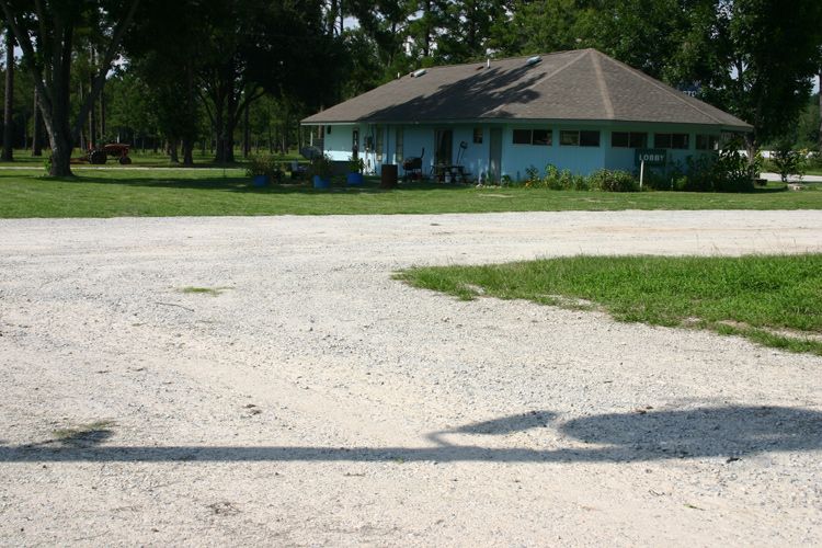 A blue house with a gray roof is surrounded by grass and trees