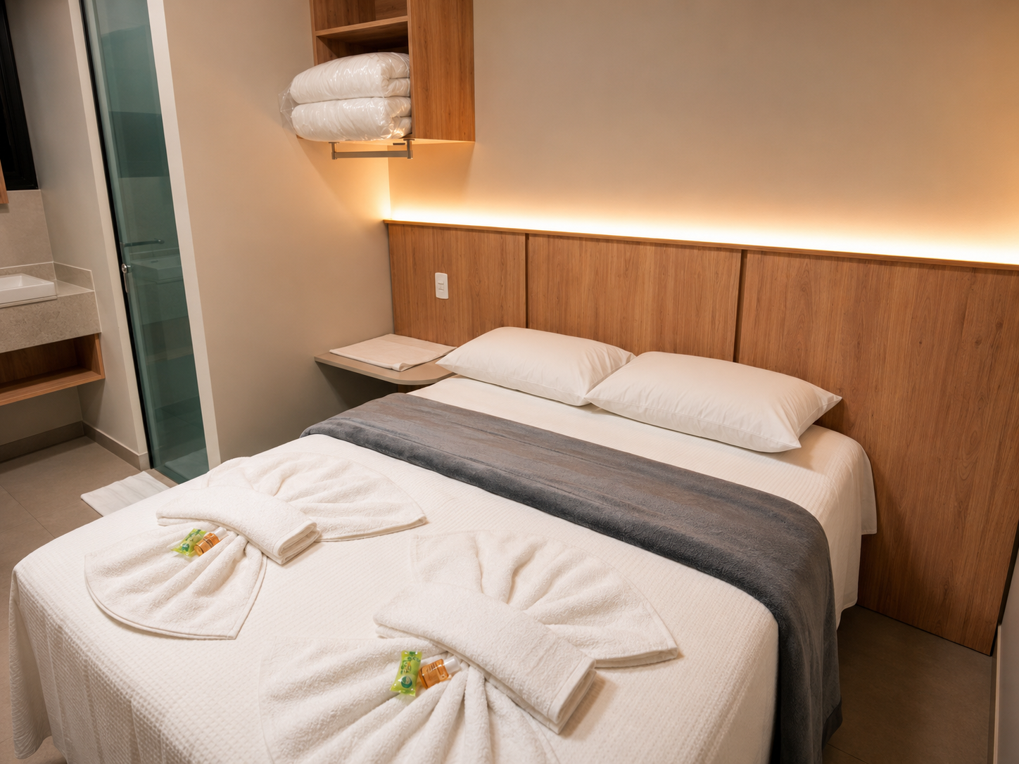 Quarto de hotel impecável com duas camas de solteiro, lençóis brancos, tapete cinza e painéis de madeira em tons quentes com iluminação suave.